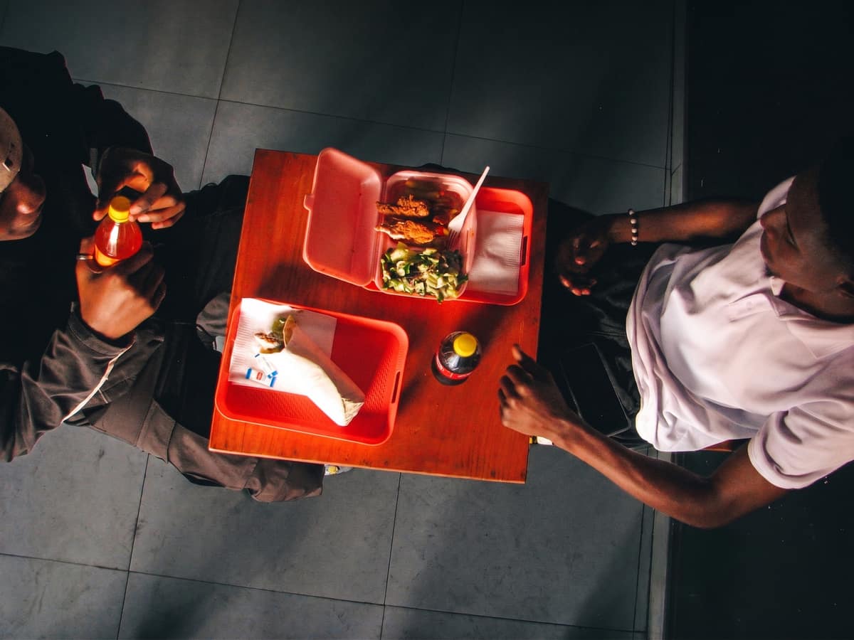 Two customers sharing a meal on the red trays at Queso Pizza in Chongwe